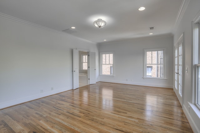 empty room with ornamental molding, plenty of natural light, and light hardwood / wood-style floors