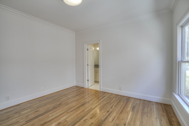 spare room with ornamental molding, plenty of natural light, and light hardwood / wood-style floors