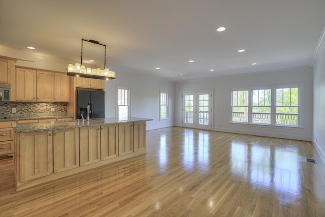 kitchen featuring light hardwood / wood-style flooring, backsplash, black fridge with ice dispenser, and hanging light fixtures