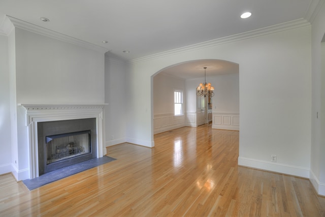 unfurnished living room featuring a notable chandelier, hardwood / wood-style floors, and crown molding