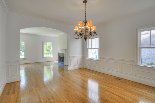 unfurnished room with an inviting chandelier, light hardwood / wood-style flooring, and crown molding