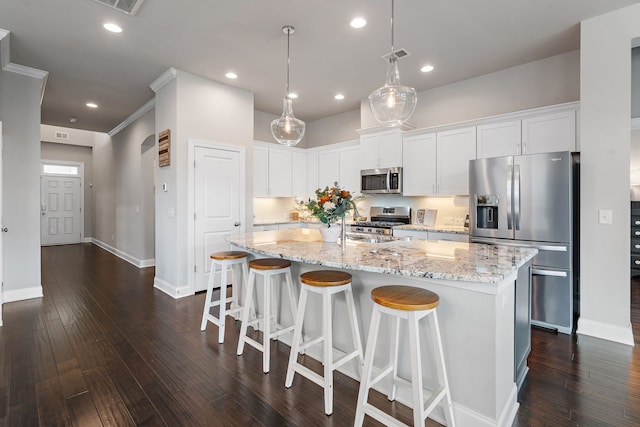 kitchen with dark hardwood / wood-style floors, an island with sink, white cabinetry, stainless steel appliances, and decorative light fixtures