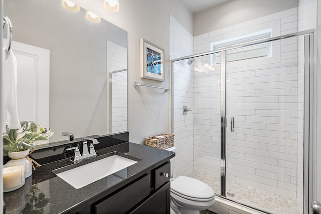 bathroom with walk in shower, vanity, and toilet