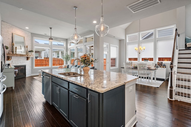 kitchen with dark wood-type flooring, sink, an island with sink, a fireplace, and ceiling fan