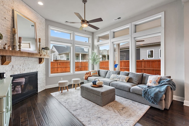 living room featuring ceiling fan, a fireplace, and dark hardwood / wood-style flooring