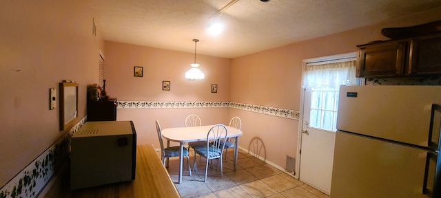 kitchen featuring light tile patterned floors, hanging light fixtures, and white fridge