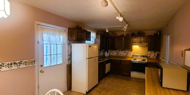 kitchen featuring white appliances, light tile patterned floors, and dark brown cabinetry