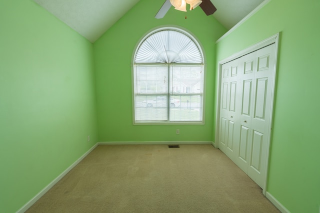 unfurnished bedroom with light carpet, vaulted ceiling, a closet, and ceiling fan