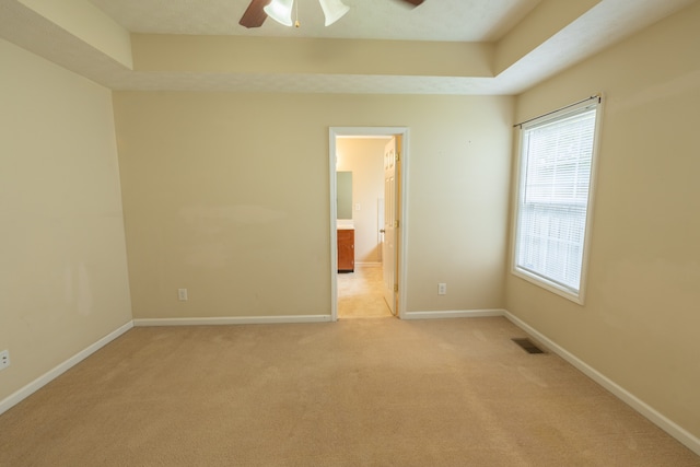 carpeted empty room featuring ceiling fan and a tray ceiling