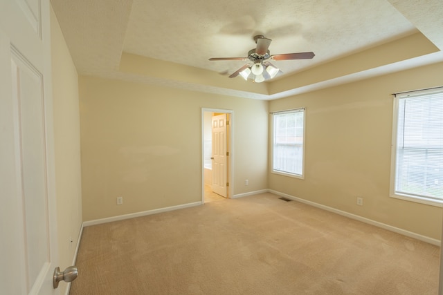 carpeted empty room featuring a textured ceiling, a raised ceiling, and ceiling fan