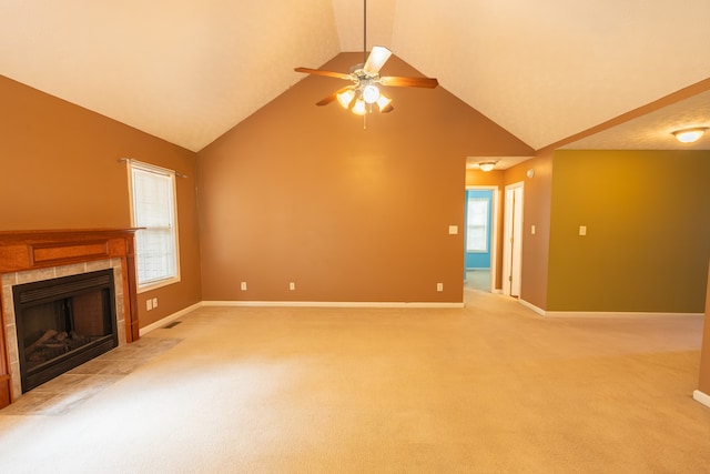 unfurnished living room with carpet floors, a tiled fireplace, ceiling fan, and high vaulted ceiling