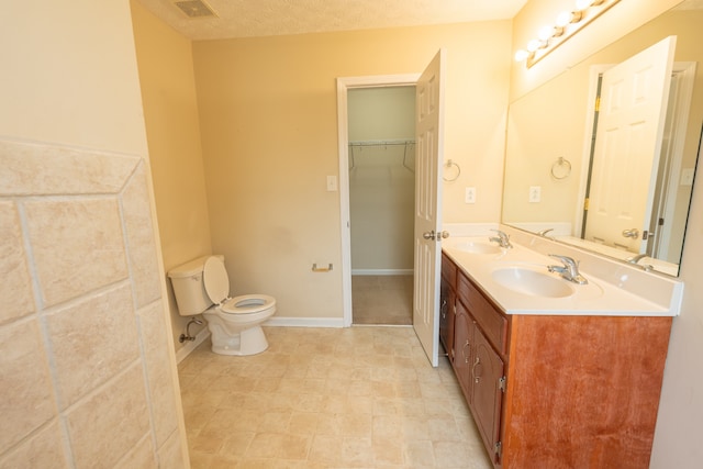 bathroom featuring a textured ceiling, vanity, and toilet