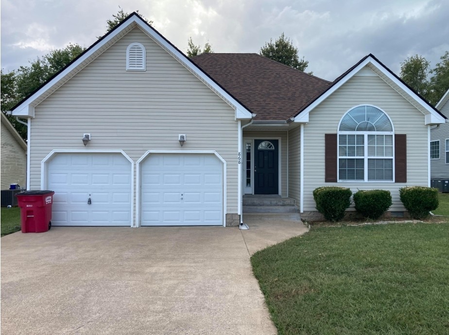 ranch-style home featuring a front yard, central air condition unit, and a garage