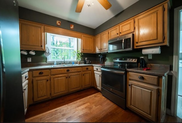 kitchen featuring ceiling fan, appliances with stainless steel finishes, sink, and light hardwood / wood-style flooring