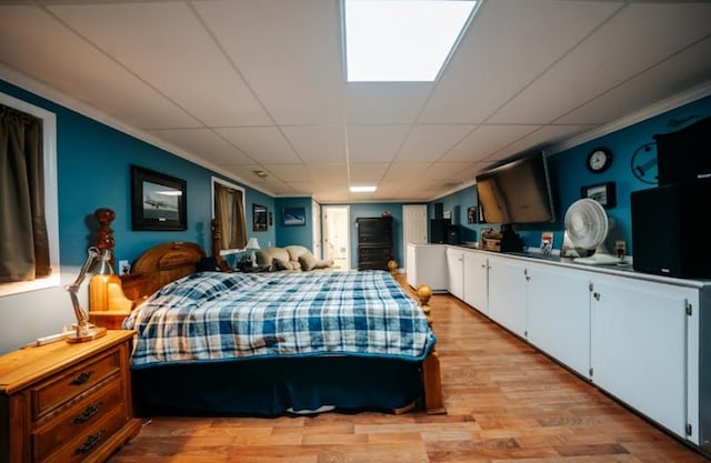 bedroom featuring crown molding, light hardwood / wood-style floors, and a drop ceiling