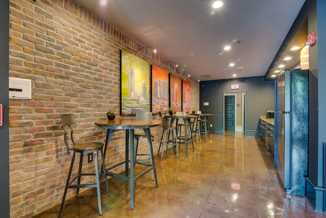 bar featuring brick wall and black refrigerator