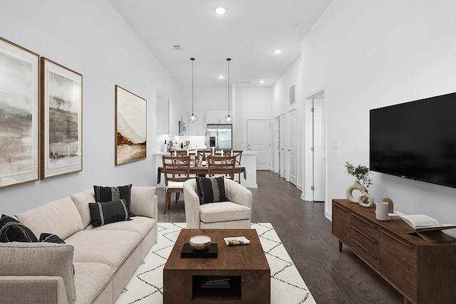 living room featuring a towering ceiling and dark wood-type flooring