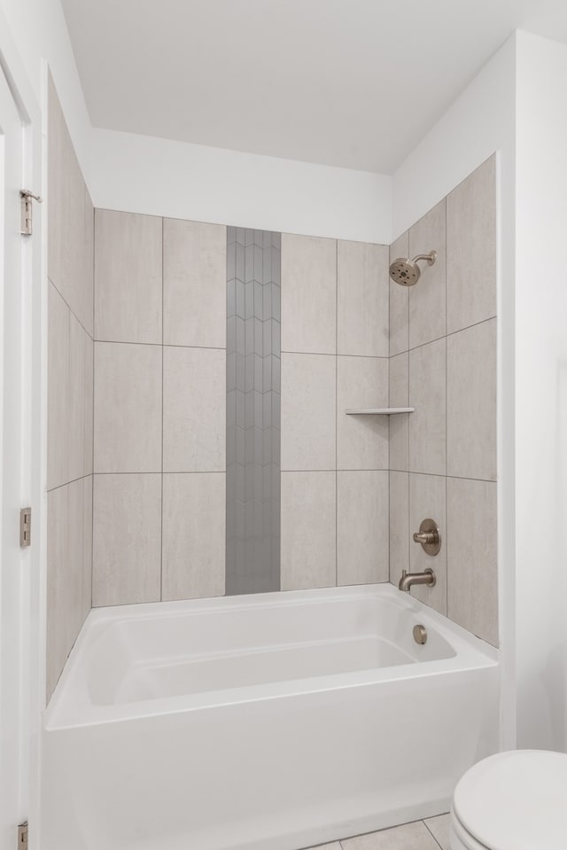 bathroom featuring tile patterned flooring, tiled shower / bath, and toilet