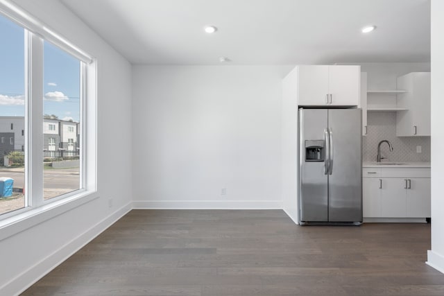 kitchen with stainless steel fridge, white cabinetry, dark wood-type flooring, tasteful backsplash, and sink