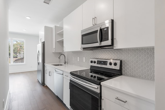 kitchen featuring sink, tasteful backsplash, dark wood-type flooring, white cabinetry, and appliances with stainless steel finishes