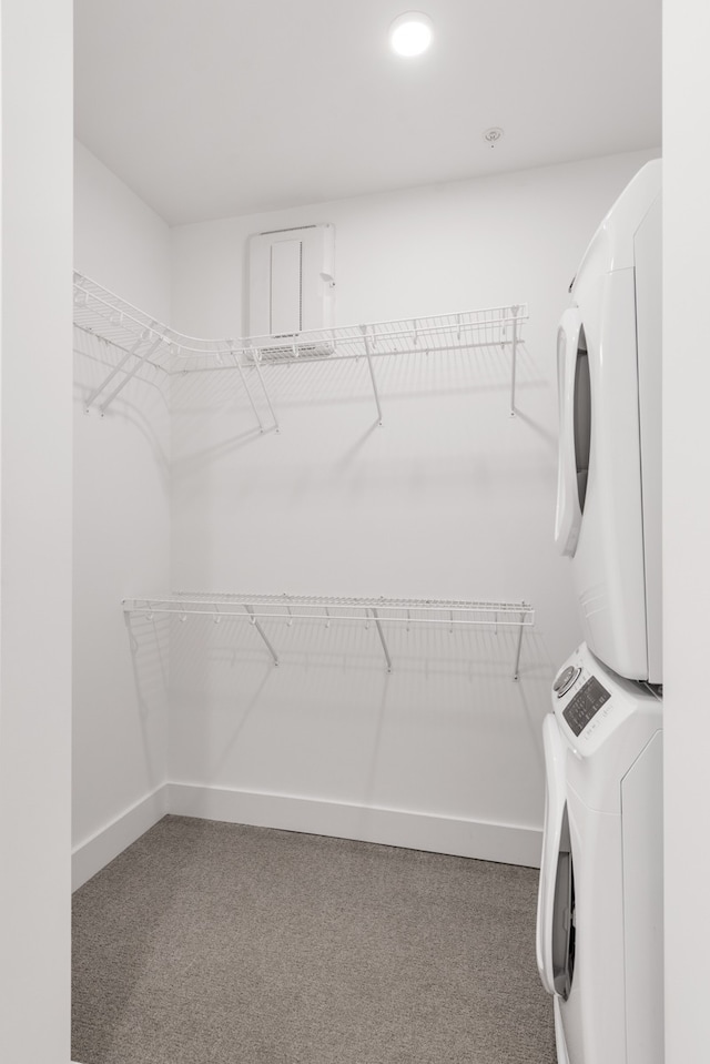 spacious closet with stacked washer / drying machine and carpet flooring