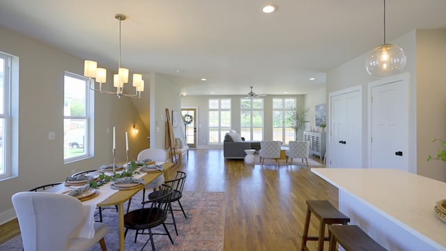 dining area featuring ceiling fan with notable chandelier and dark wood-type flooring