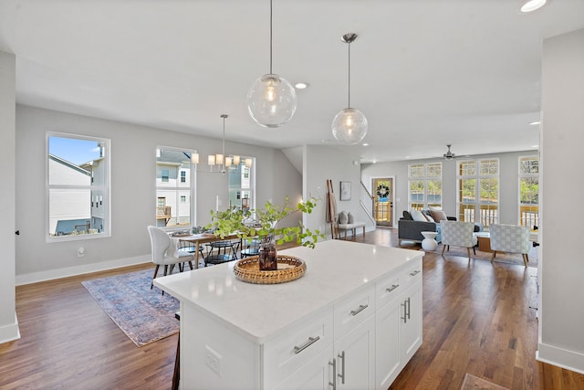 kitchen with white cabinets, plenty of natural light, a kitchen island, and dark hardwood / wood-style flooring