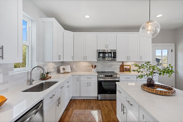 kitchen featuring white cabinets, dark hardwood / wood-style flooring, stainless steel appliances, decorative light fixtures, and sink