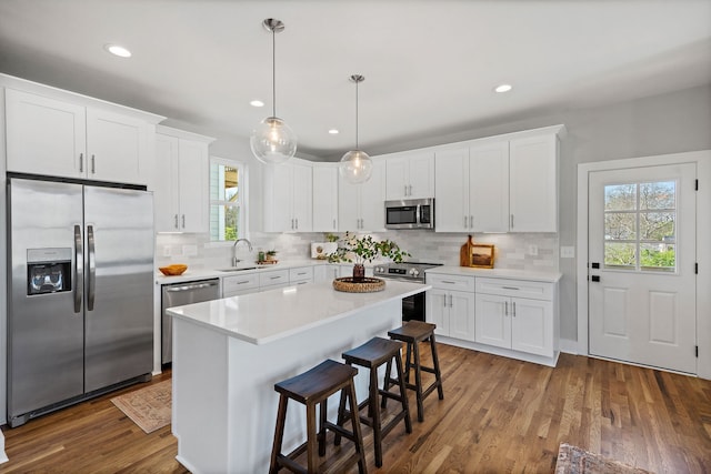 kitchen featuring appliances with stainless steel finishes, white cabinetry, and hardwood / wood-style flooring