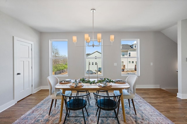 dining area featuring a notable chandelier, vaulted ceiling, and dark wood-type flooring