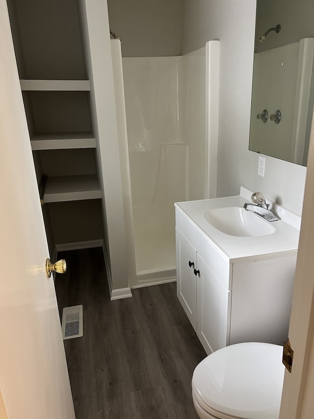 bathroom featuring walk in shower, vanity, toilet, and hardwood / wood-style flooring