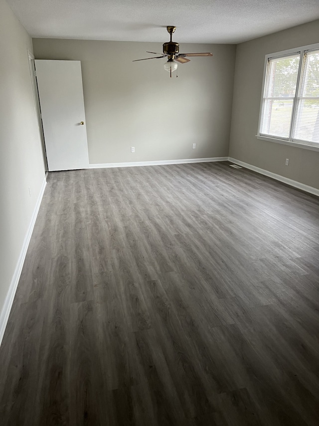 unfurnished room featuring ceiling fan, dark wood-type flooring, and a textured ceiling