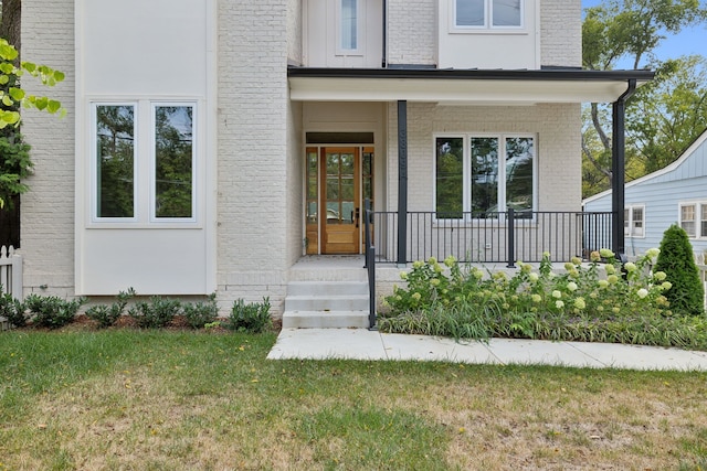 doorway to property featuring covered porch and a yard