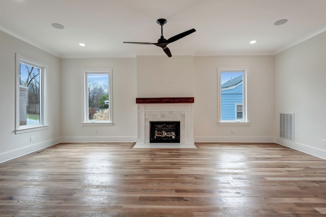 unfurnished living room with ornamental molding, light hardwood / wood-style floors, a tile fireplace, and ceiling fan