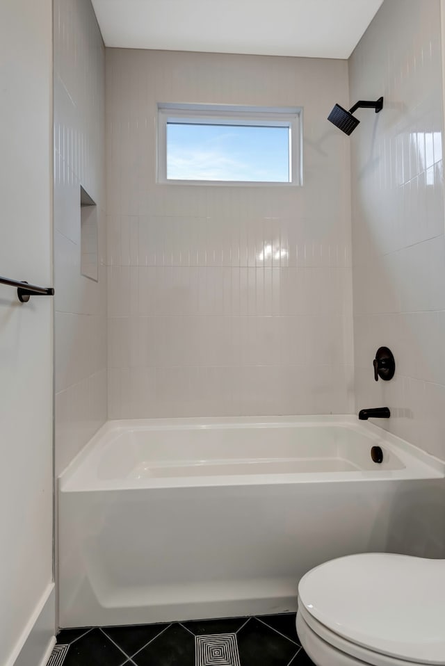 bathroom with tiled shower / bath combo, tile patterned floors, and toilet