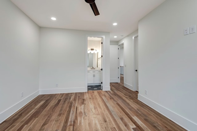 unfurnished bedroom with connected bathroom, sink, ceiling fan, and hardwood / wood-style flooring