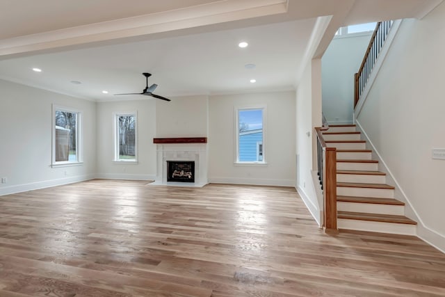 unfurnished living room featuring ceiling fan, crown molding, light hardwood / wood-style floors, and a high end fireplace