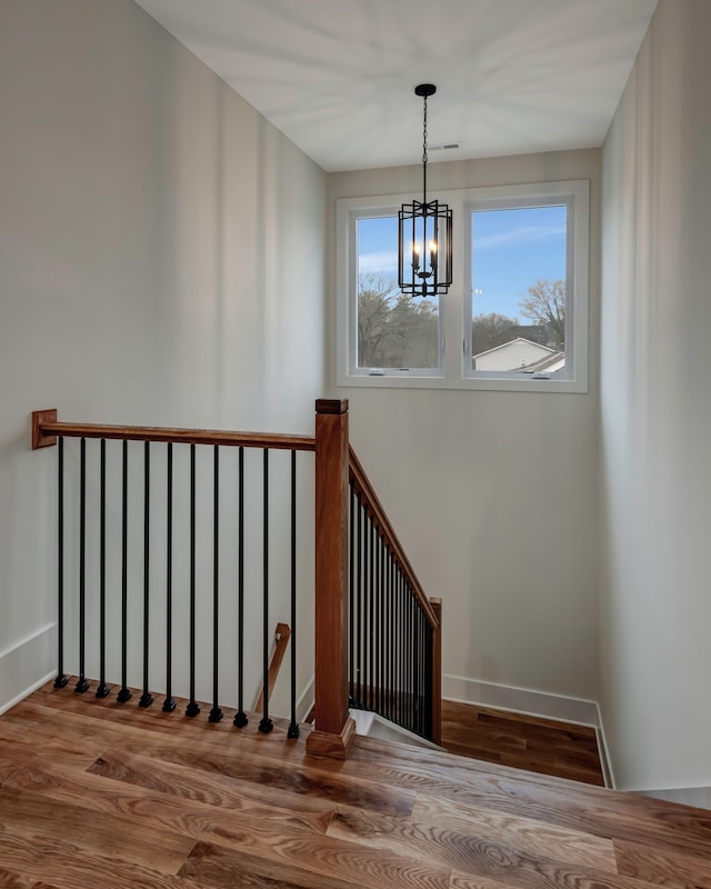 stairway with an inviting chandelier and hardwood / wood-style floors