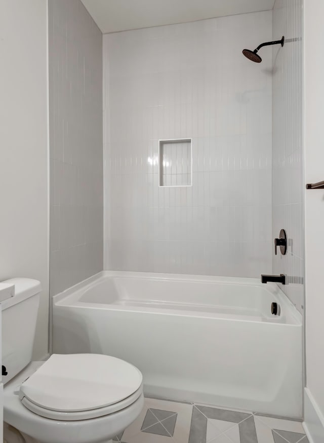 bathroom with tiled shower / bath combo, tile patterned flooring, and toilet