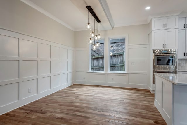 unfurnished dining area with a notable chandelier, light wood-type flooring, and crown molding