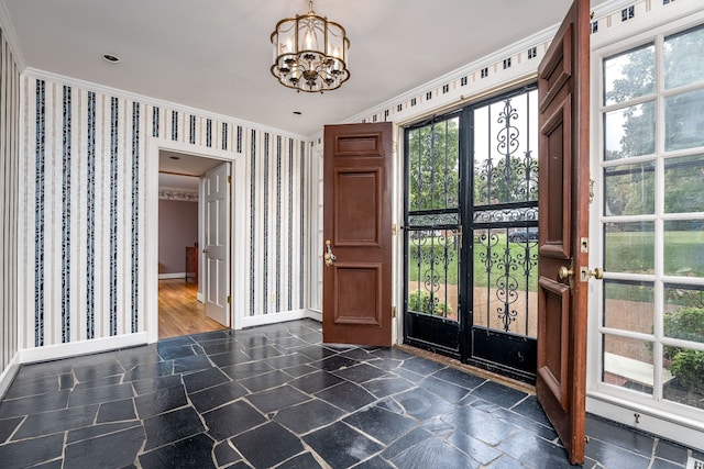 foyer with an inviting chandelier, crown molding, and a healthy amount of sunlight