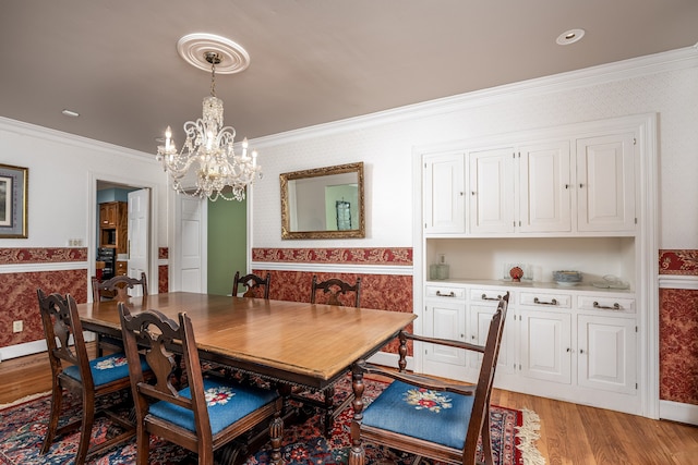 dining area with an inviting chandelier, light wood-type flooring, and ornamental molding