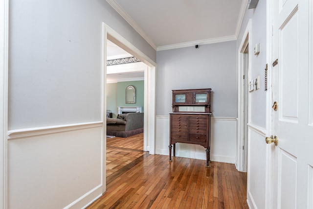 corridor with ornamental molding and hardwood / wood-style flooring