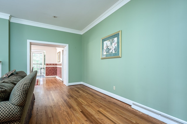 empty room featuring a baseboard radiator, hardwood / wood-style flooring, and crown molding