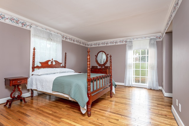 bedroom with ornamental molding and light hardwood / wood-style floors