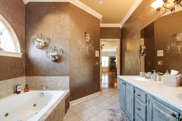 bathroom featuring vanity, a relaxing tiled tub, ornamental molding, and tile patterned floors