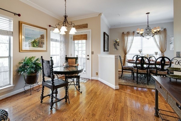 dining area featuring wood-type flooring, a notable chandelier, and crown molding