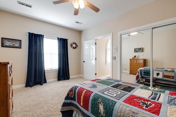 bedroom with light carpet, ceiling fan, and a closet