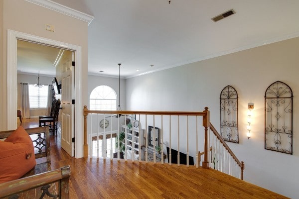 corridor with an inviting chandelier, ornamental molding, and hardwood / wood-style floors