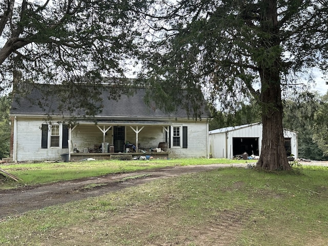 view of front of home with covered porch, a front lawn, a garage, and an outbuilding